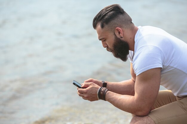 Человек, используя свой мобильный телефон на берегу озера