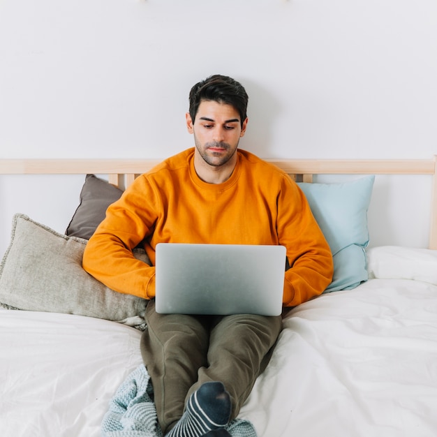 Man using laptop on bed