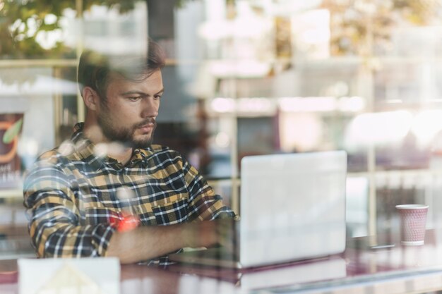 Uomo che utilizza computer portatile nella caffetteria