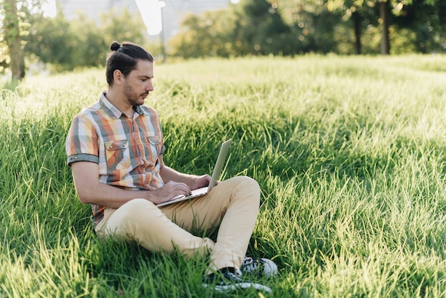 Foto gratuita uomo che utilizza computer portatile nel parco