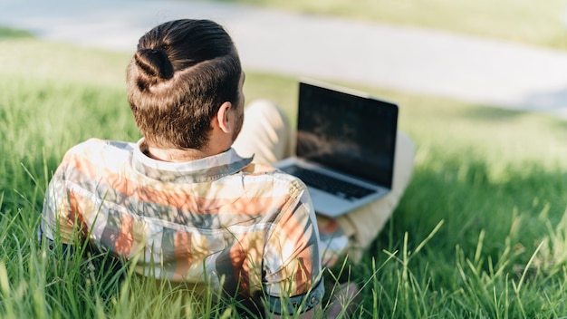 Free photo man using laptop in park