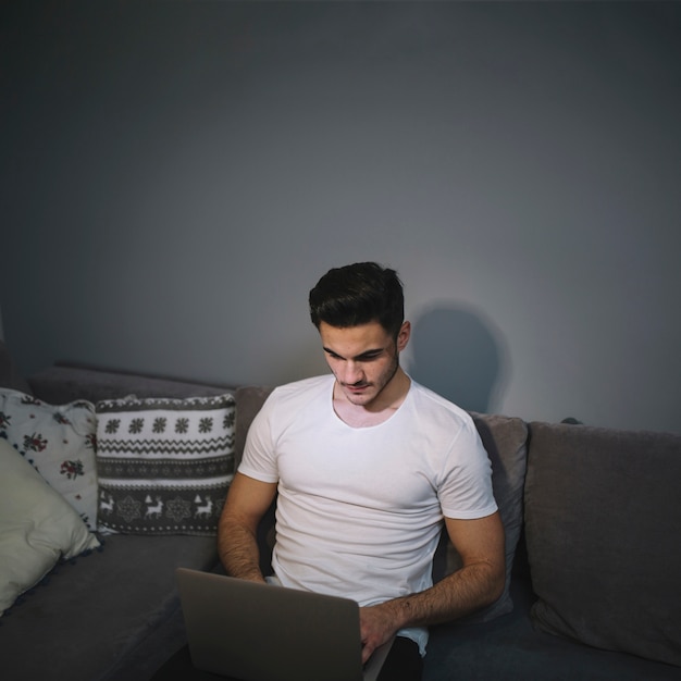 Man using laptop on sofa