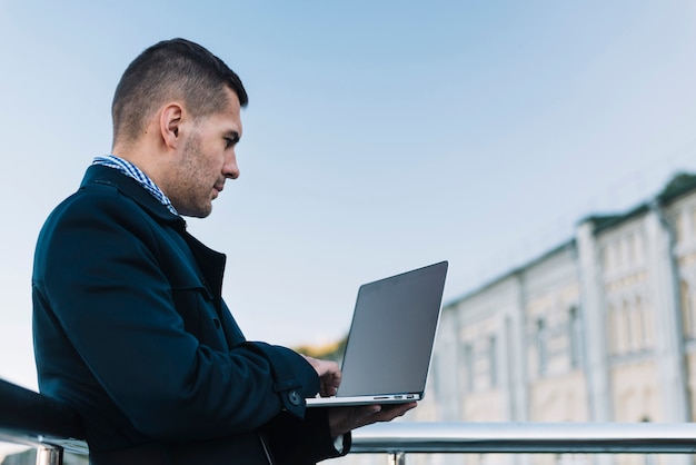 Foto gratuita uomo che utilizza computer portatile in ambiente urbano