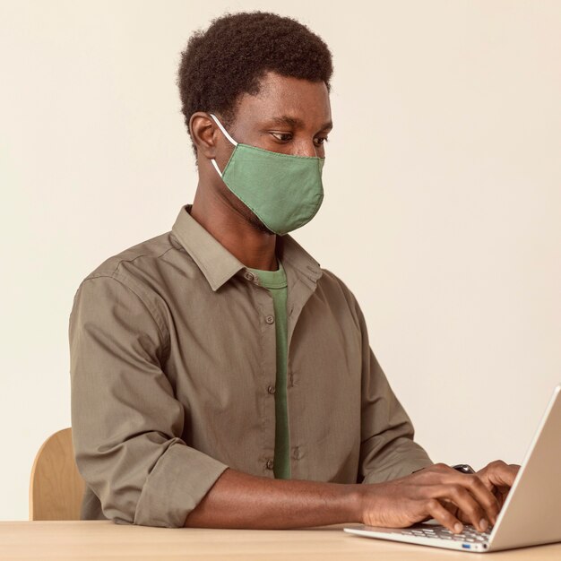 Человек, использующий ноутбук и носящий маску