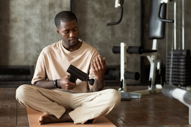 Man using massage gun on forearm full shot