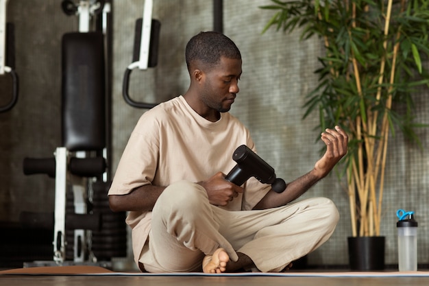 Free photo man using massage gun on forearm low angle