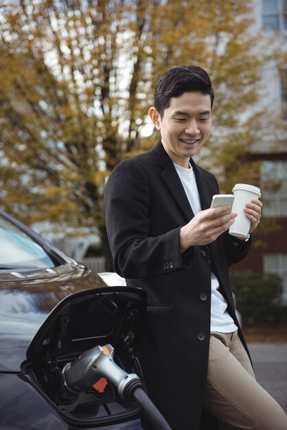 Man using mobile phone while charging car