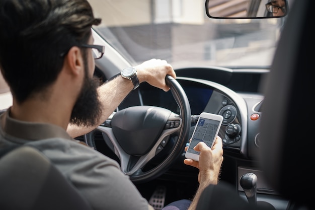 Free photo man using mobile phone while driving.