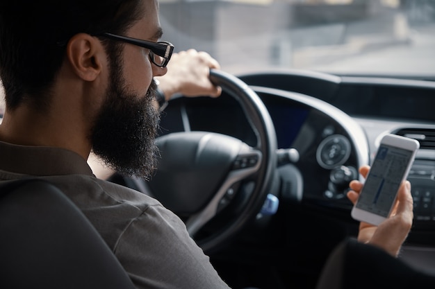 Человек с помощью мобильного телефона во время вождения.
