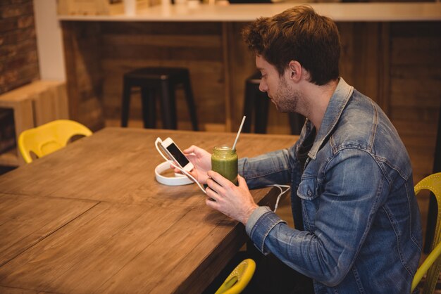 ジュースを持ちながら携帯電話を使用している人