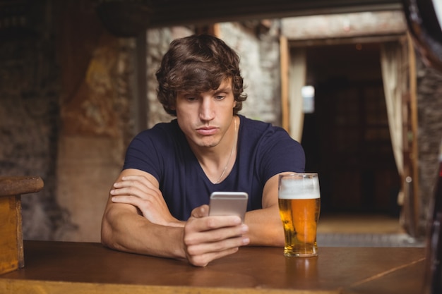 Man using mobile phone with beer glass on table