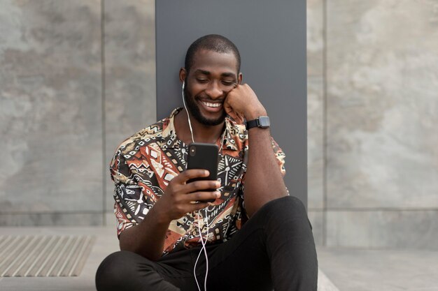 Man using modern smartphone with earphones