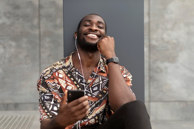 Man using modern smartphone with earphones