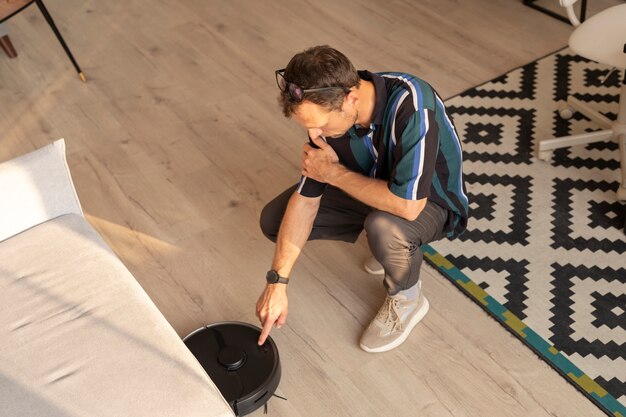 Man using a robot vacuum in the living room