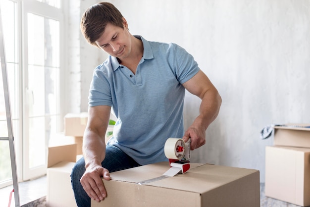 Man using scotch tape on box to secure it for moving out