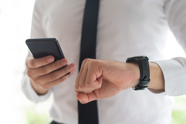 Uomo che usando smartphone e controllando il tempo