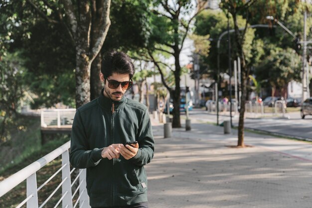 Man using smartphone near fence