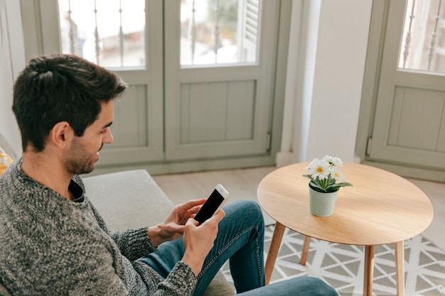 Free photo man using smartphone on sofa