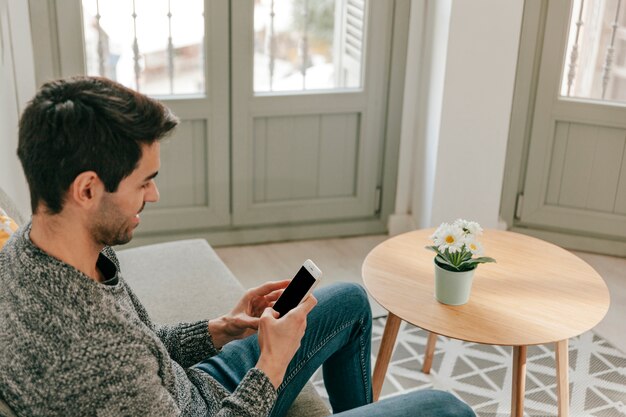 Man using smartphone on sofa