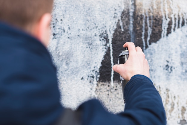 Man using spray for drawing graffiti on wall