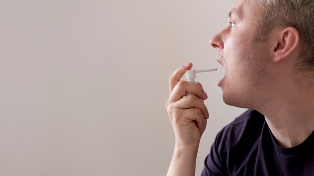Man using treatment for sore throat copy space