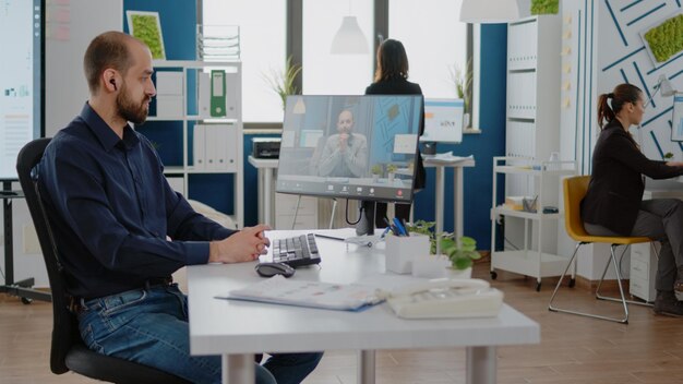 コンピューターのマネージャーとの会議にビデオ通話を使用している男性。事業開発と仮想マーケティングのためのウェブカメラとのオンラインリモート会議でトレーナーと話している企業の従業員