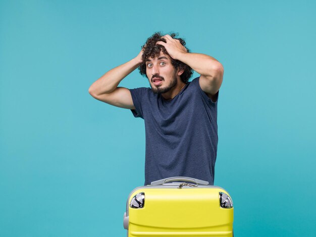 man in vacation in blue t-shirt holding his head on blue