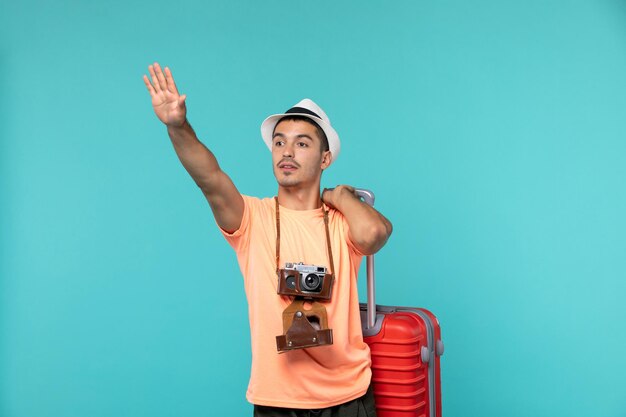 man in vacation holding big red suitcase on blue