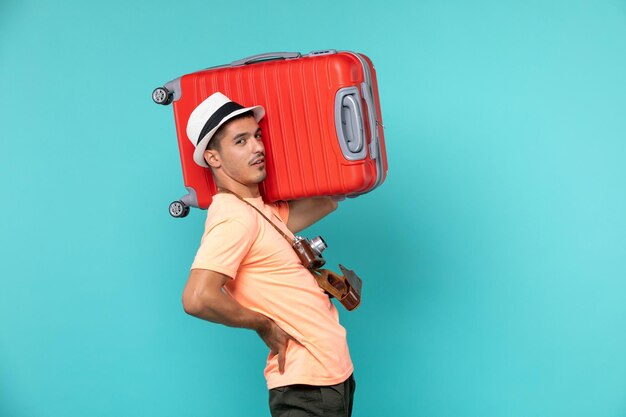 青に大きな赤いスーツケースを持って休暇中の男