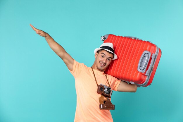 man in vacation holding big red suitcase on blue