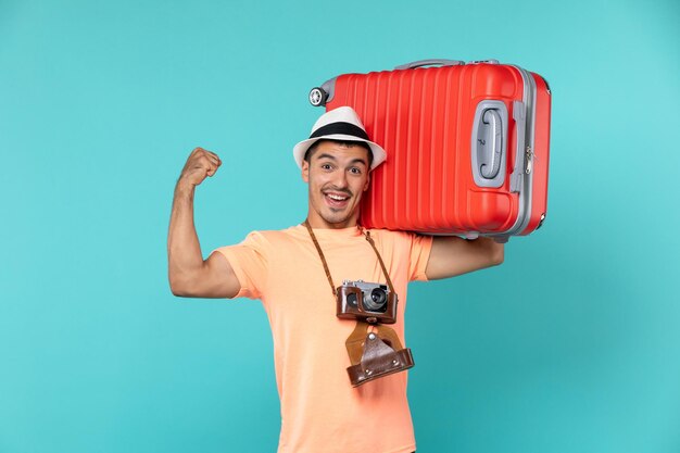 человек в отпуске держит большой красный чемодан на синем