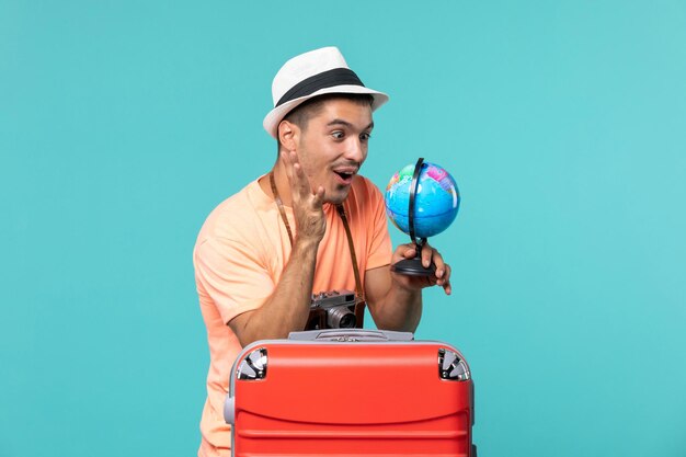 man in vacation holding globe and taking photos with camera on blue