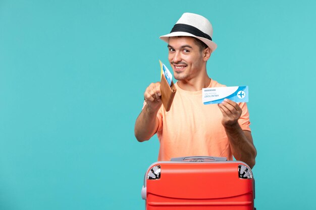 man in vacation holding his ticket and smiling on blue