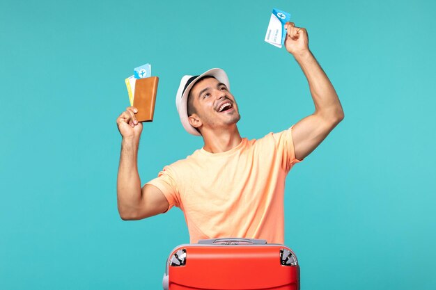 man in vacation holding his tickets and rejoicing on blue