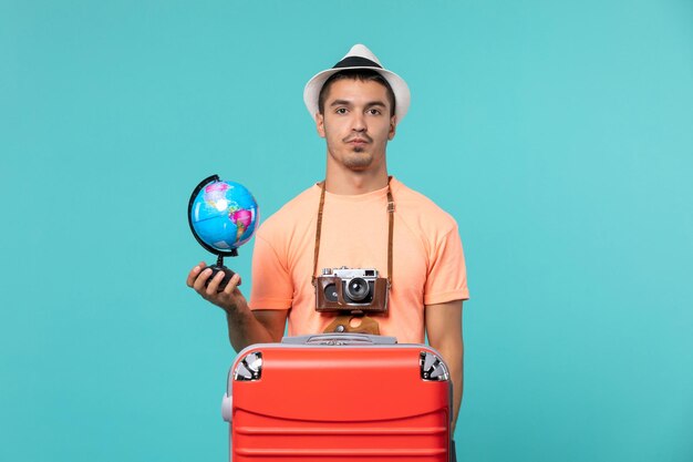 Uomo in vacanza che tiene un piccolo globo su blue