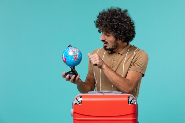 man in vacation holding little globe on blue