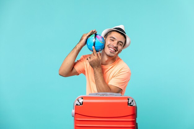 man in vacation holding little globe on light blue