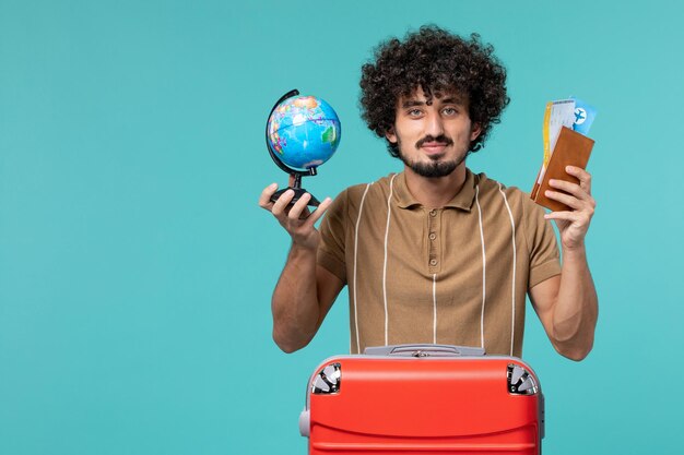 man in vacation holding little globe and ticket on blue