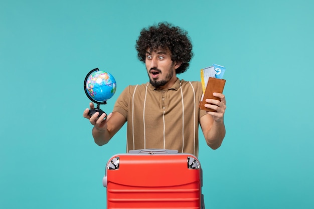 man in vacation holding little globe and ticket on blue