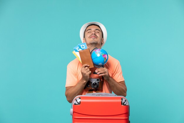 man in vacation holding little globe and tickets on blue