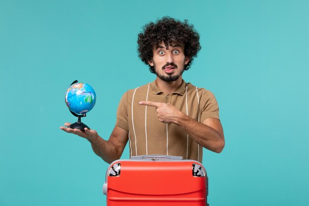 man in vacation holding little globe with red bag on blue