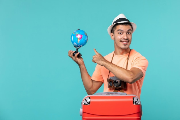 man in vacation holding little globe with smile on blue