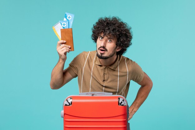 man in vacation holding tickets on blue wall