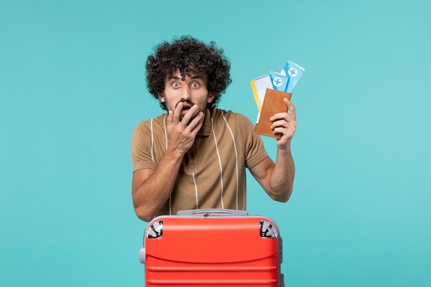 man in vacation holding tickets on blue