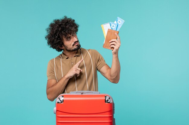 man in vacation holding tickets on blue