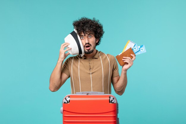 man in vacation holding tickets on blue