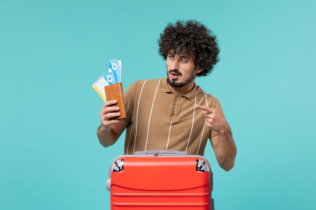 man in vacation holding tickets on light-blue