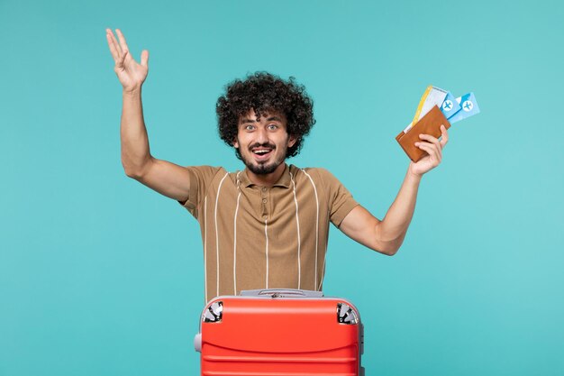 man in vacation holding tickets on light blue