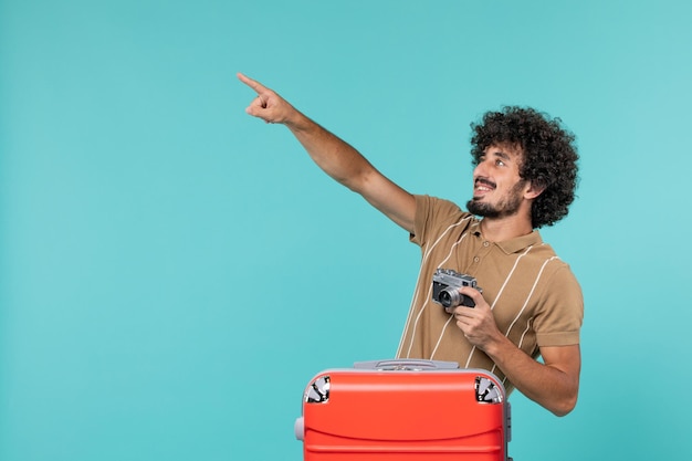 человек в отпуске с большим красным чемоданом фотографирует с камерой на голубом