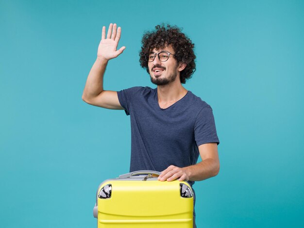 man in vacation with big suitcase on light blue